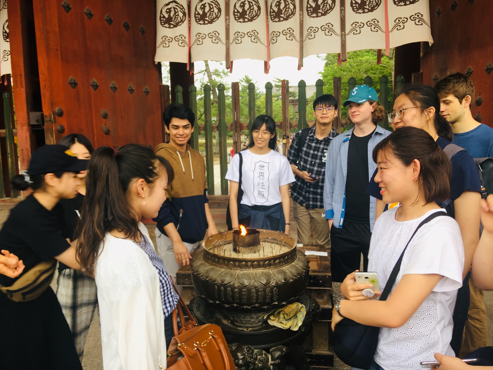 Students standing around a pot holding lit incense