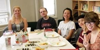 Group of students sitting at table, looking at the camera